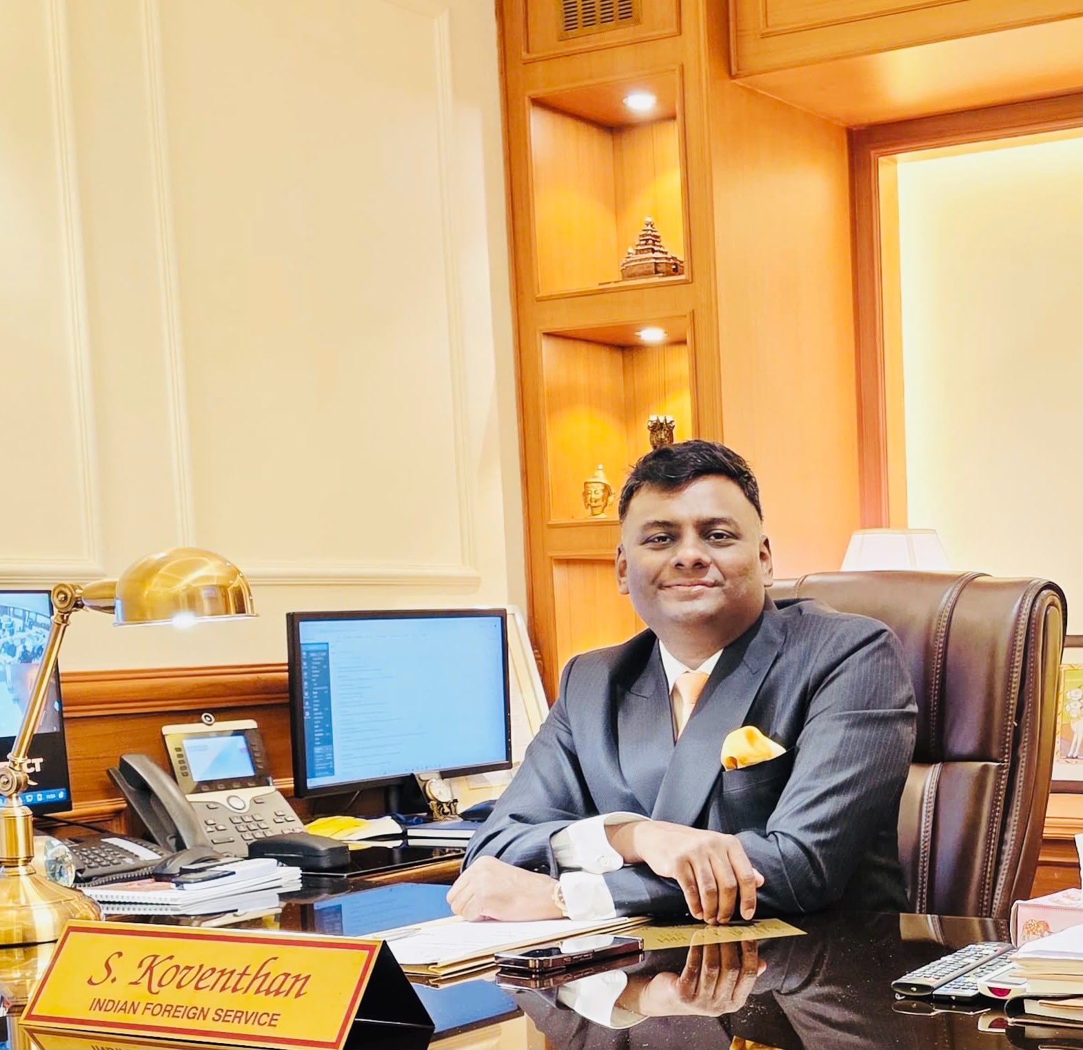His Excellency S. Koventhan seated at his desk with the Indian flag